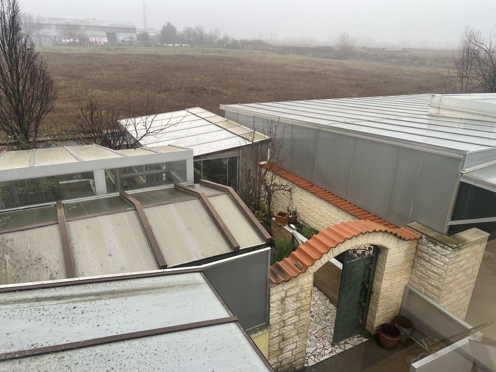 Blick von oben auf verschiedene Dachkonstruktionen und einen kleinen ummauerten Gartenbereich mit Tor.