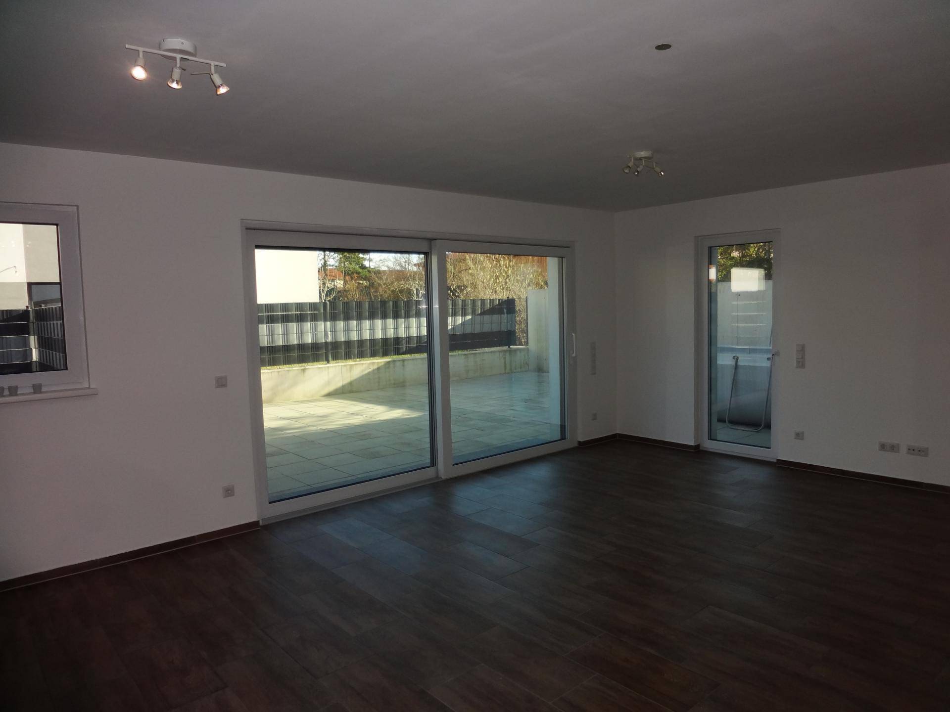 Helles Wohnzimmer mit großen Schiebetüren zum Außenbereich und dunklem Fliesenboden.