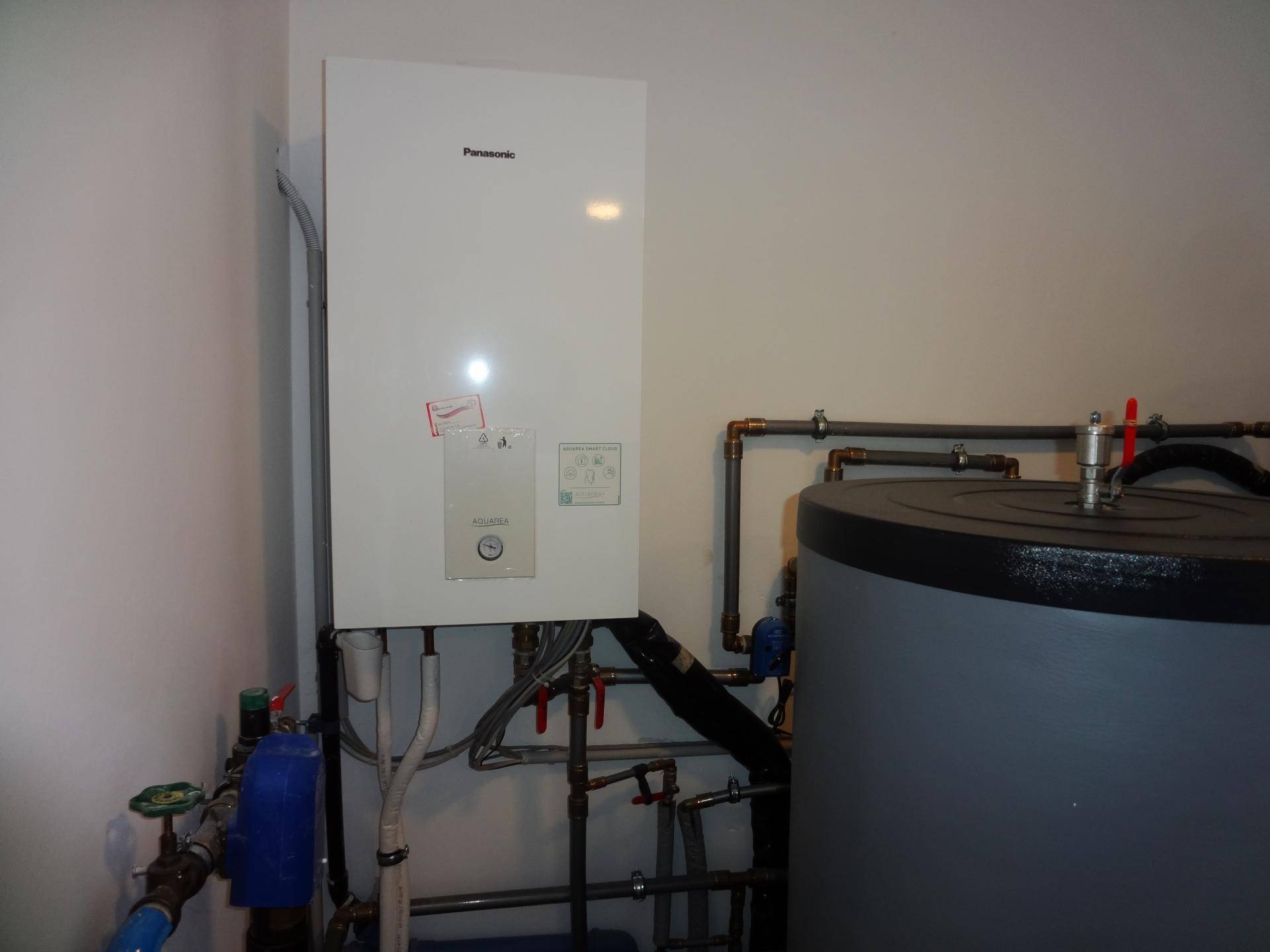 Heizungsraum mit Panasonic-Wärmepumpe und Warmwasserspeicher für effiziente Energieversorgung.