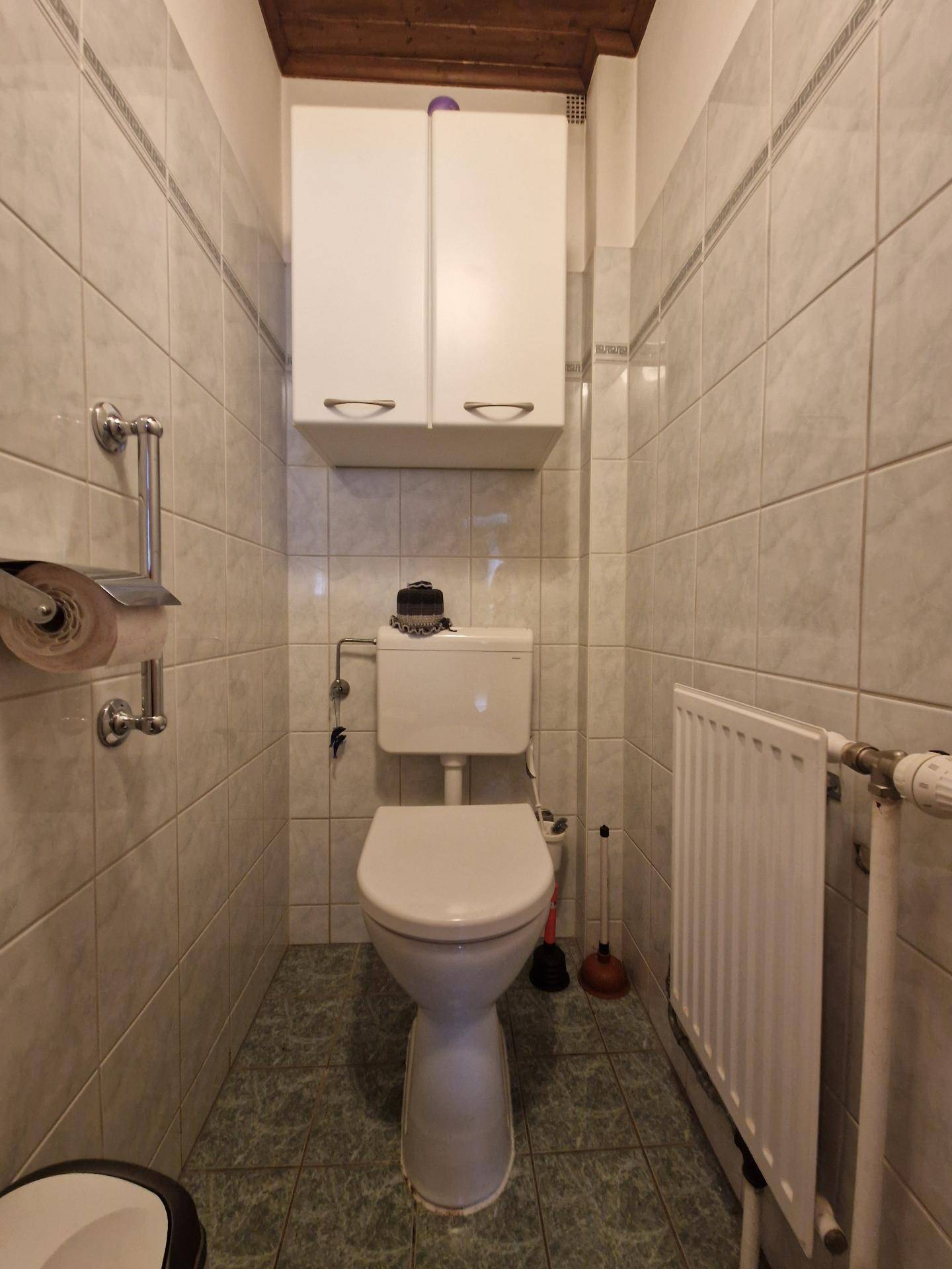 Kleines Gäste-WC mit Fliesen an Wänden und Boden.