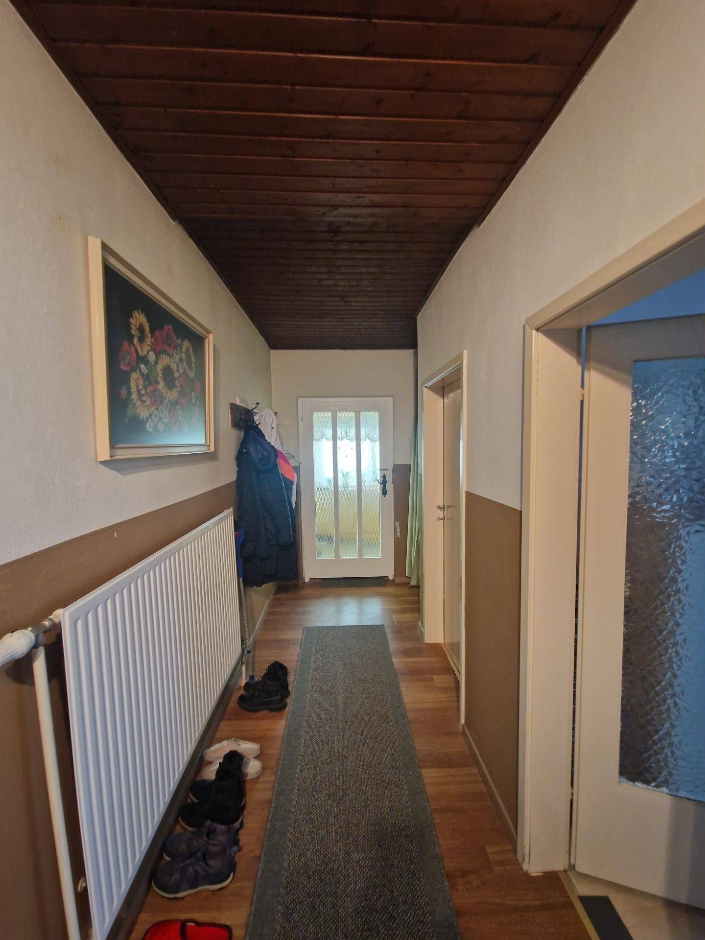 Langer Flur mit Holzdeckenverkleidung und Teppichläufer.