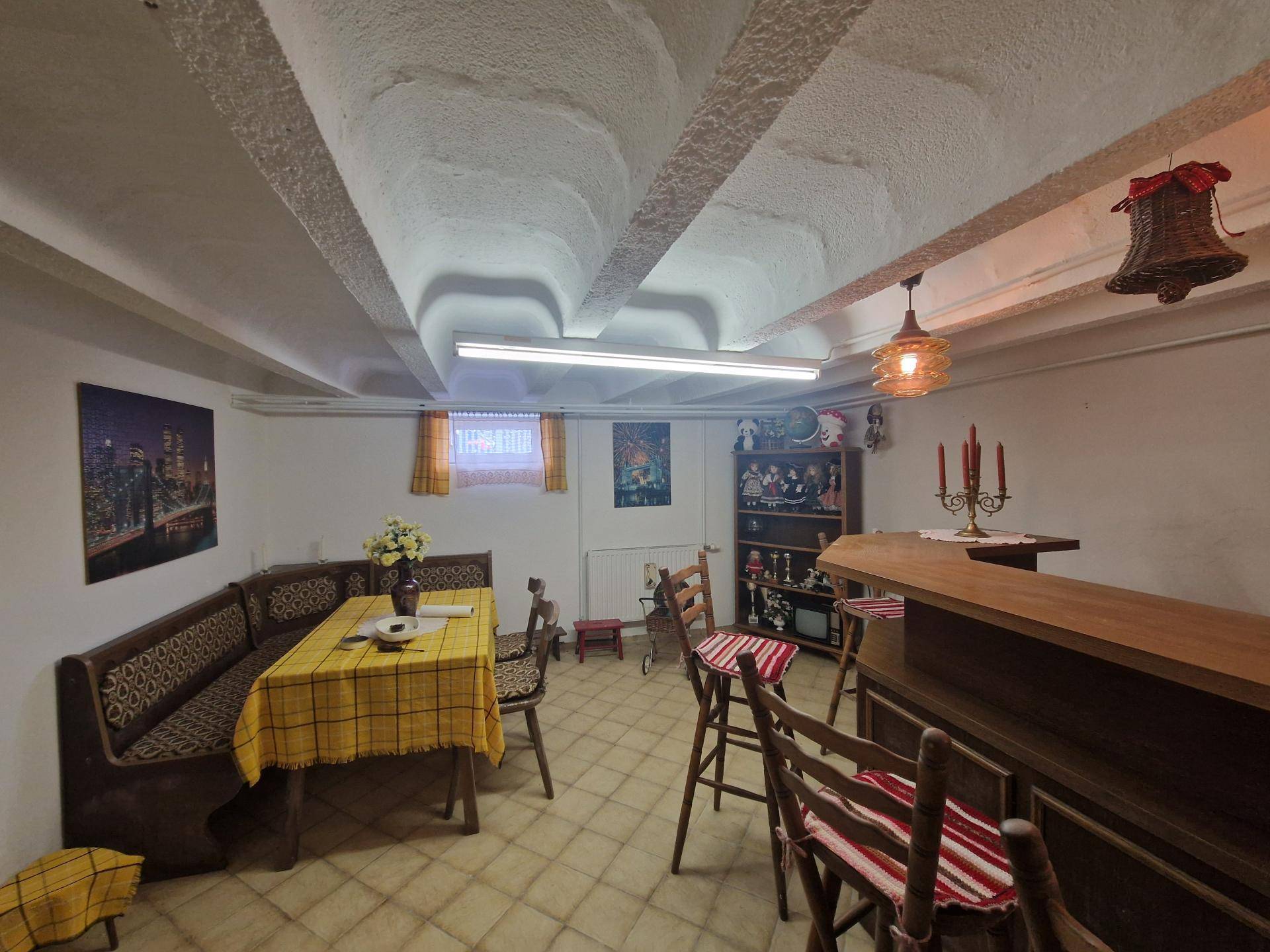 Rustikaler Partyraum im Keller mit Bar, Sitzecke und traditioneller Dekoration.