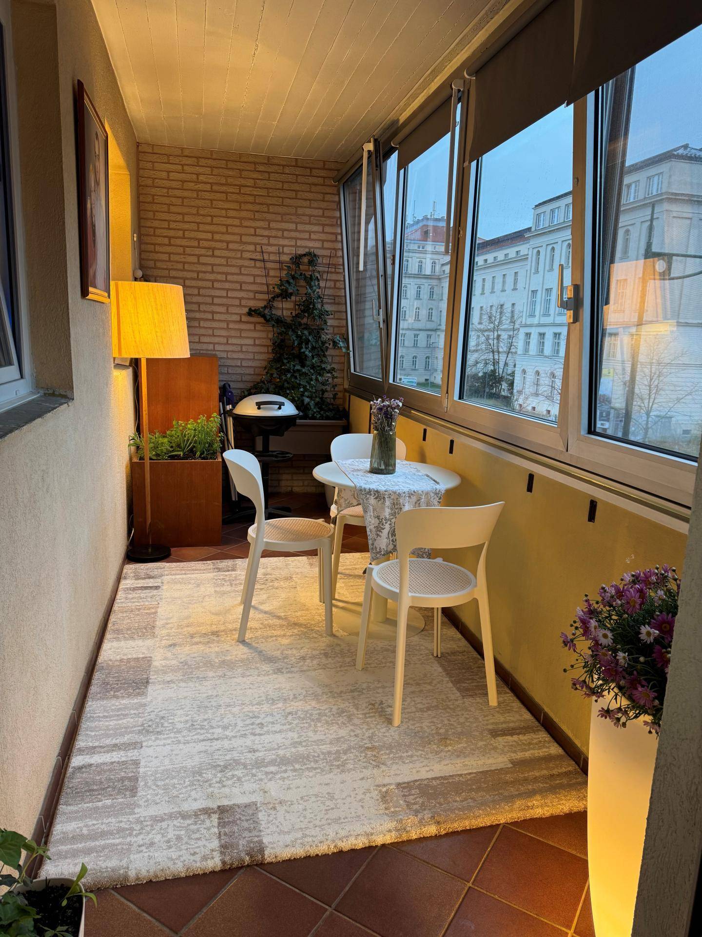 Helle Loggia mit Fliesenboden, Sitzgelegenheiten und Blick auf die Stadt.
