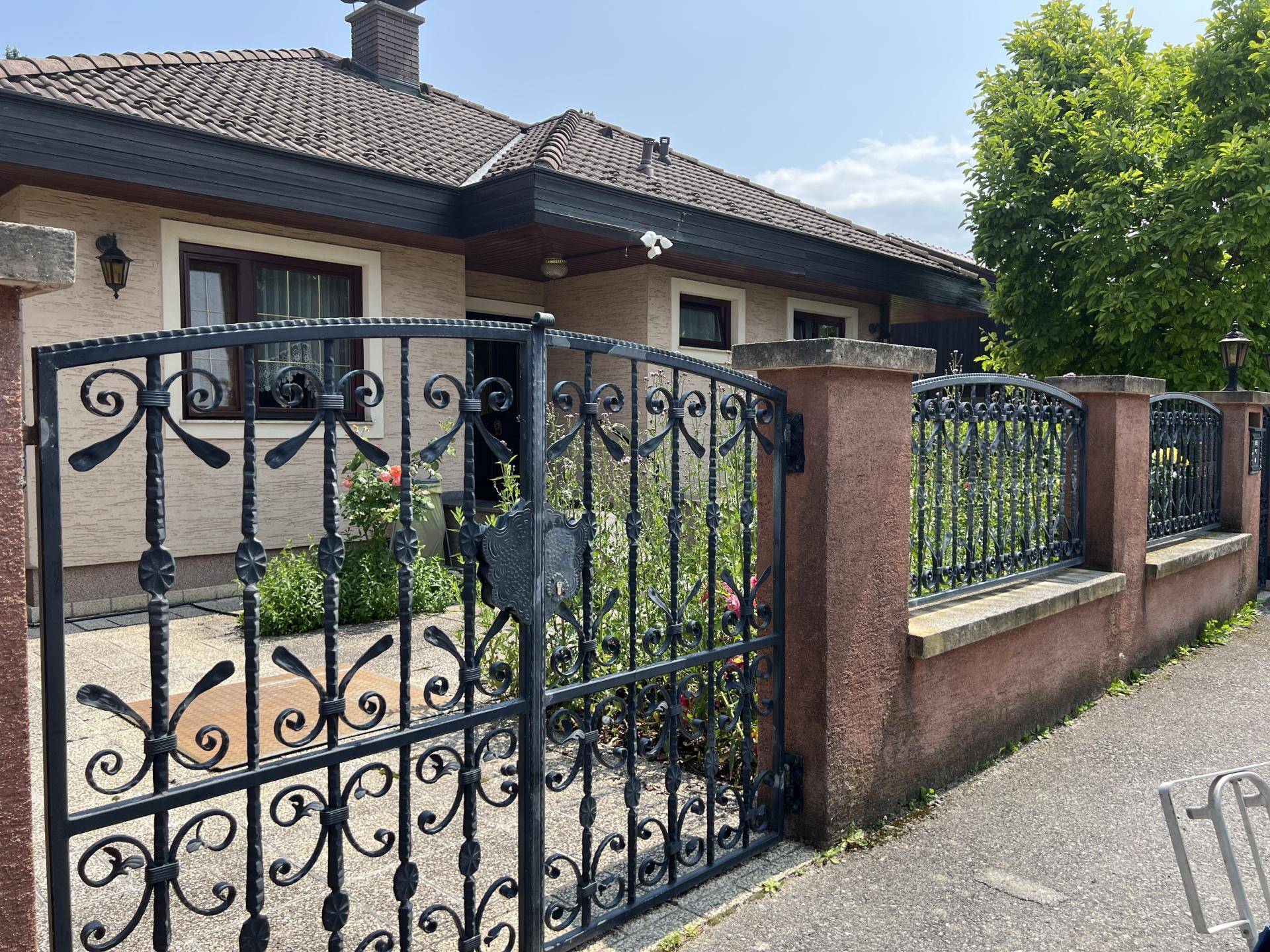 Geschmiedetes Eingangstor mit dekorativen Elementen und Blick auf die Hausfassade.