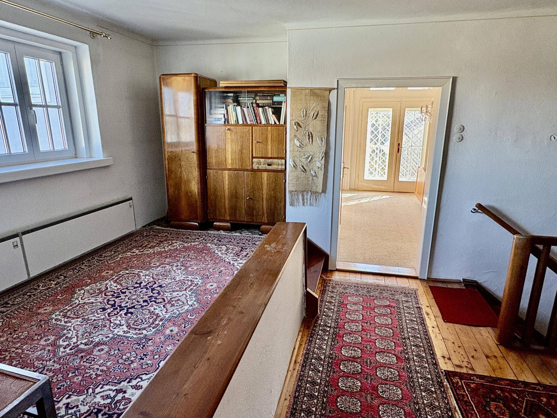 Heller Flur im Obergeschoss mit Holzfußboden, Teppichen und einem Schrank, der zu einem weiteren Raum führt.