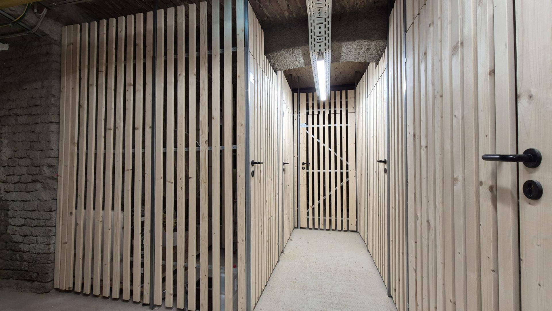 Kellerabteile mit Holzlattenwänden und Metalltüren, ideal für zusätzlichen Stauraum.