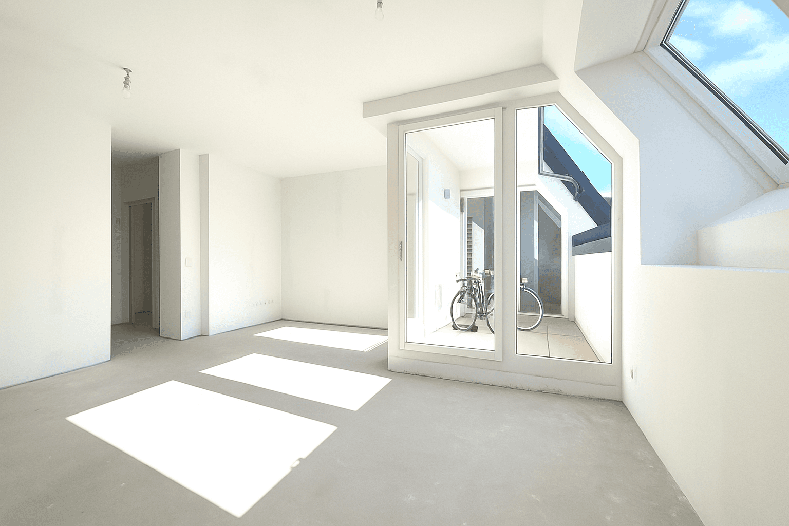 Geräumiger, heller Raum im Dachgeschoss mit Zugang zu einem Balkon und viel Tageslicht.