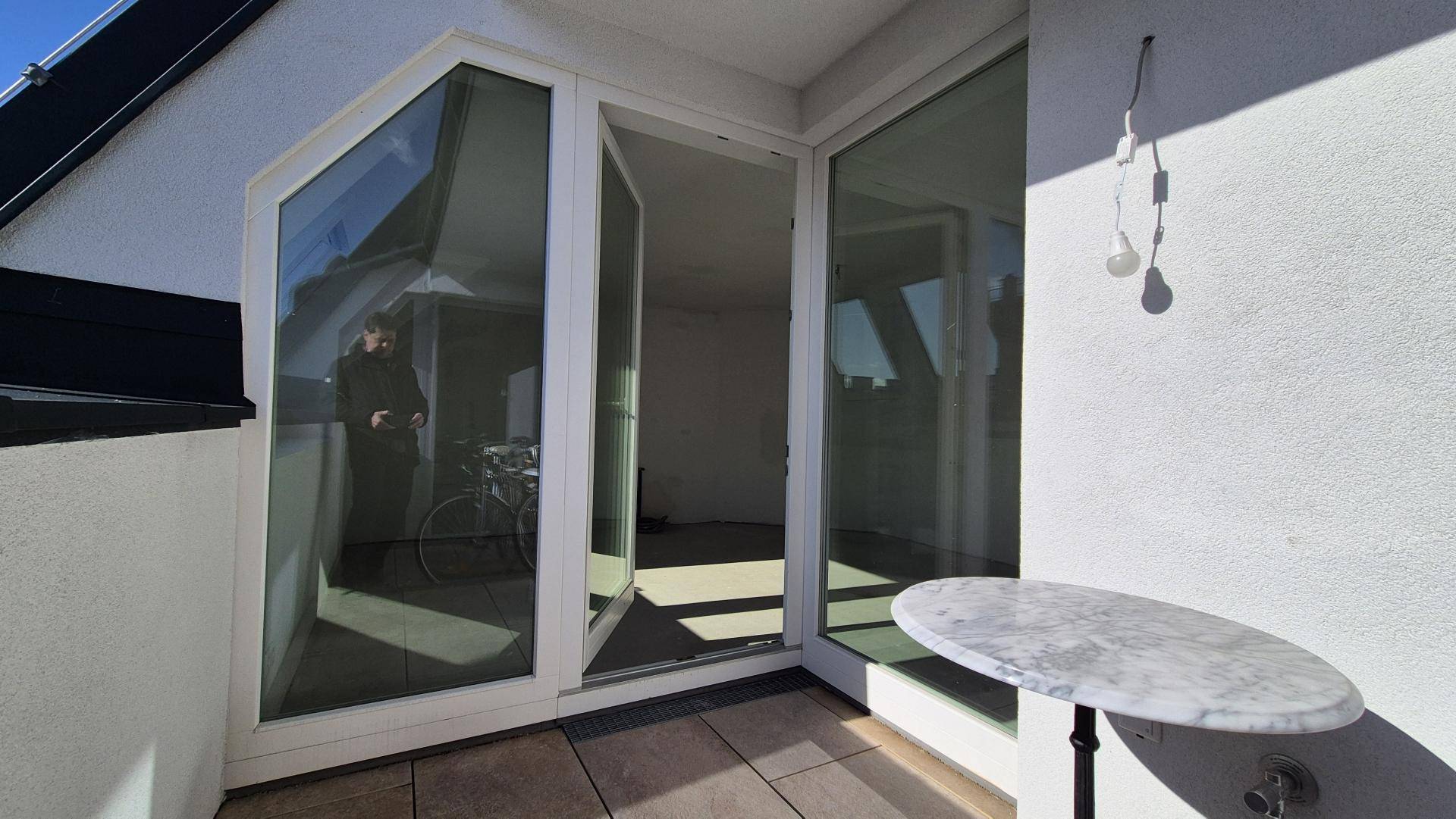 Kleiner Balkon mit Marmortisch und Blick auf die Umgebung, zugänglich vom Innenraum.