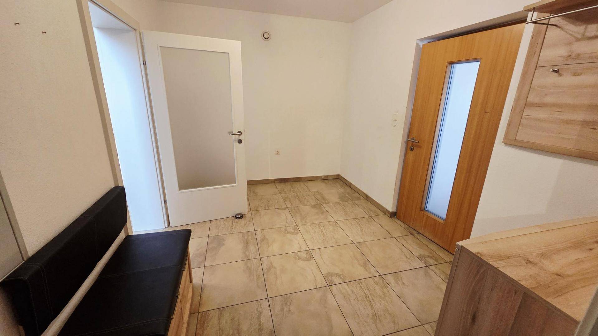 Heller Eingangsbereich mit Fliesenboden, Garderobe und modernen Türen.