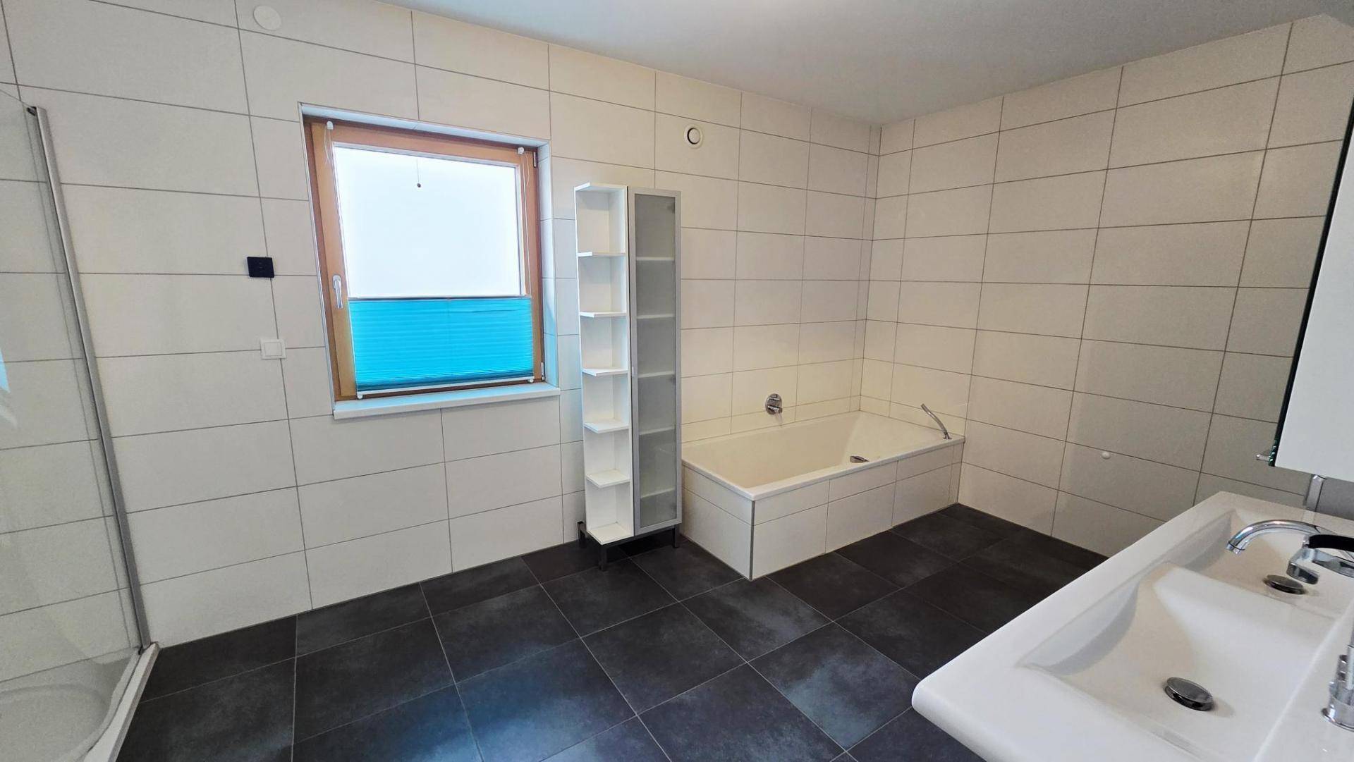 Geräumiges Badezimmer mit Badewanne, Dusche, Waschbecken und Fenster.