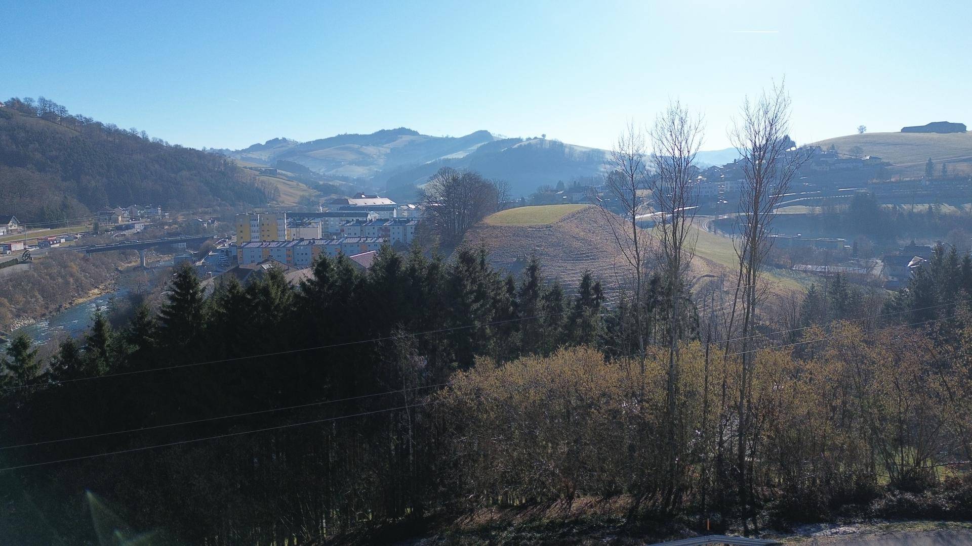 Weitläufiger Blick über die hügelige Landschaft mit Wäldern und einem Fluss.
