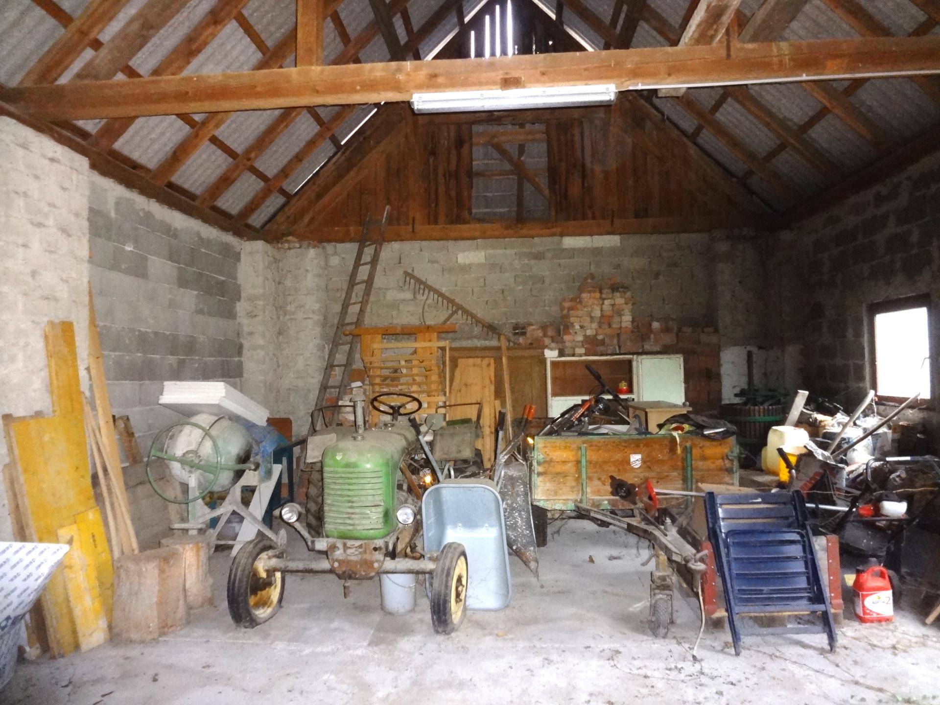 Große Scheune oder Garage mit landwirtschaftlichen Geräten und Baumaterialien.