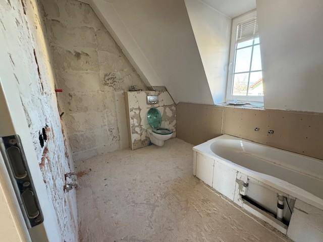 Badezimmer im Rohbau mit Badewanne und Toilette, bereit für den Ausbau.