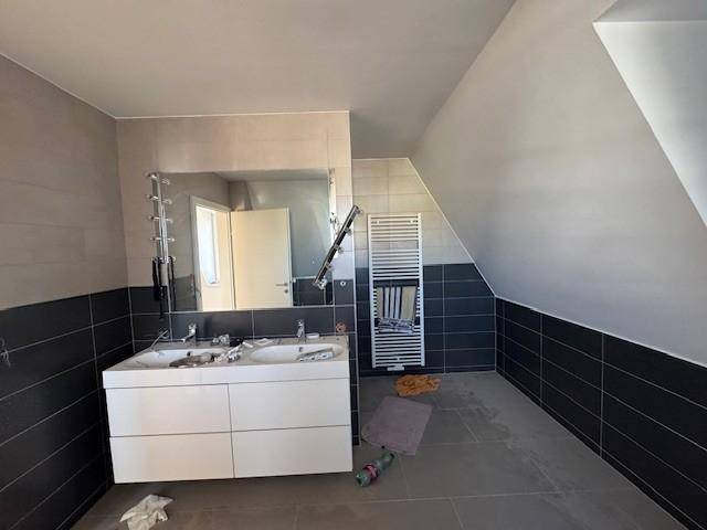 Modernes Badezimmer im Dachgeschoss mit Doppelwaschbecken, Handtuchheizkörper und schrägen Wänden.