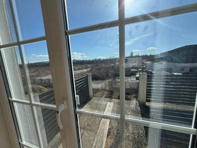 Blick aus dem Fenster auf die Umgebung mit einem Balkongeländer und weitem Horizont.