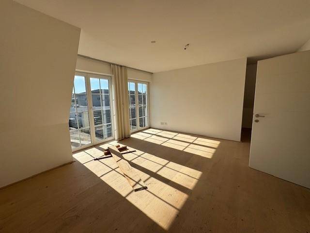Geräumiges Schlafzimmer im Dachgeschoss mit Holzboden und direktem Zugang zum Balkon.