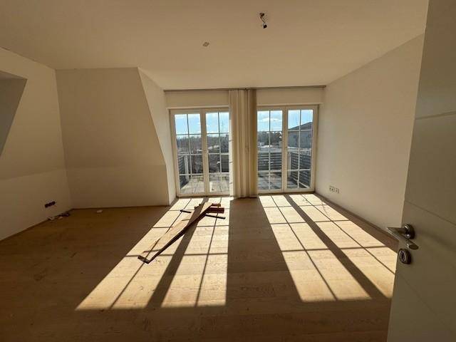 Helles Schlafzimmer im Dachgeschoss mit Holzboden und direktem Zugang zum Balkon.