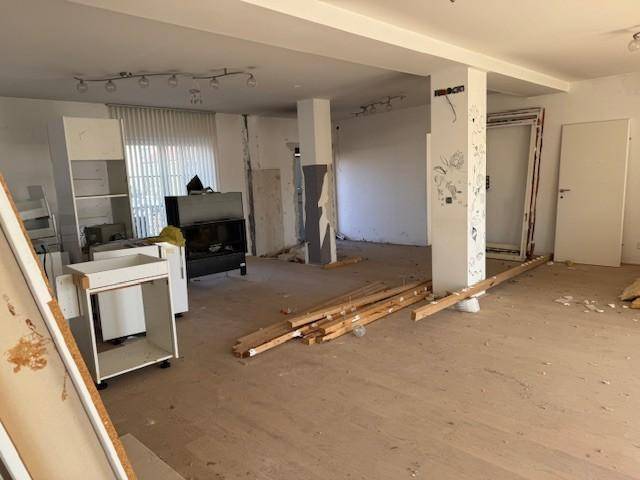 Geräumiger Wohnbereich im Rohbau mit Säulen und Baumaterialien, bereit für den Innenausbau.