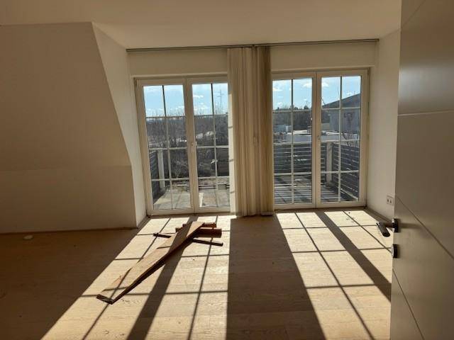 Helles Schlafzimmer im Dachgeschoss mit Holzboden, Balkonzugang und viel Sonnenlicht.