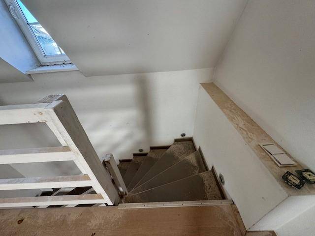 Treppenaufgang mit Holzgeländer und Oberlicht, das natürliches Licht spendet.