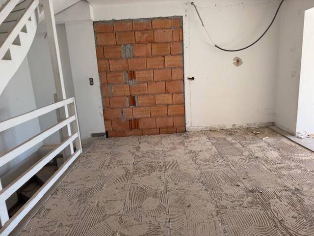 Flur im Rohbau mit Treppenaufgang und unverputzter Ziegelwand, bereit für den Innenausbau.