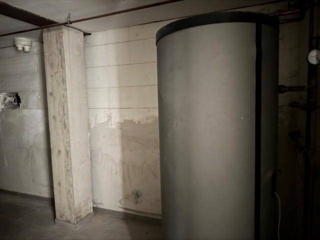 Kellerraum mit Warmwasserspeicher, Betonwänden und sichtbaren Installationen.