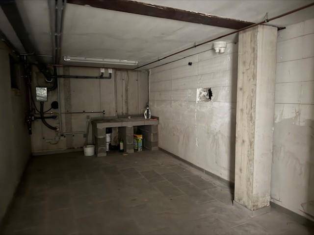 Kellerraum mit Betonwänden, einfacher Arbeitsplatte und sichtbaren Installationen.