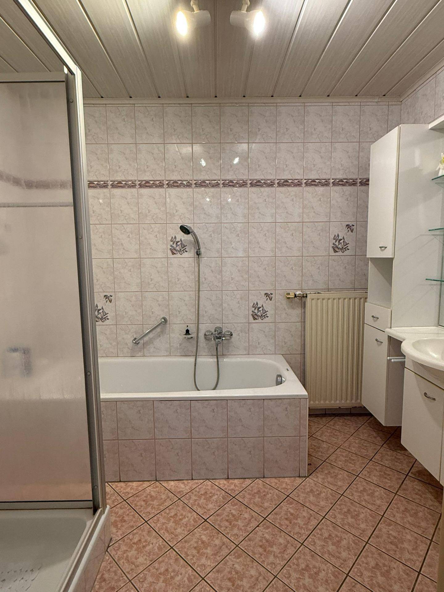 Badezimmer mit Badewanne, Duschkabine und hellen Fliesen im traditionellen Stil.