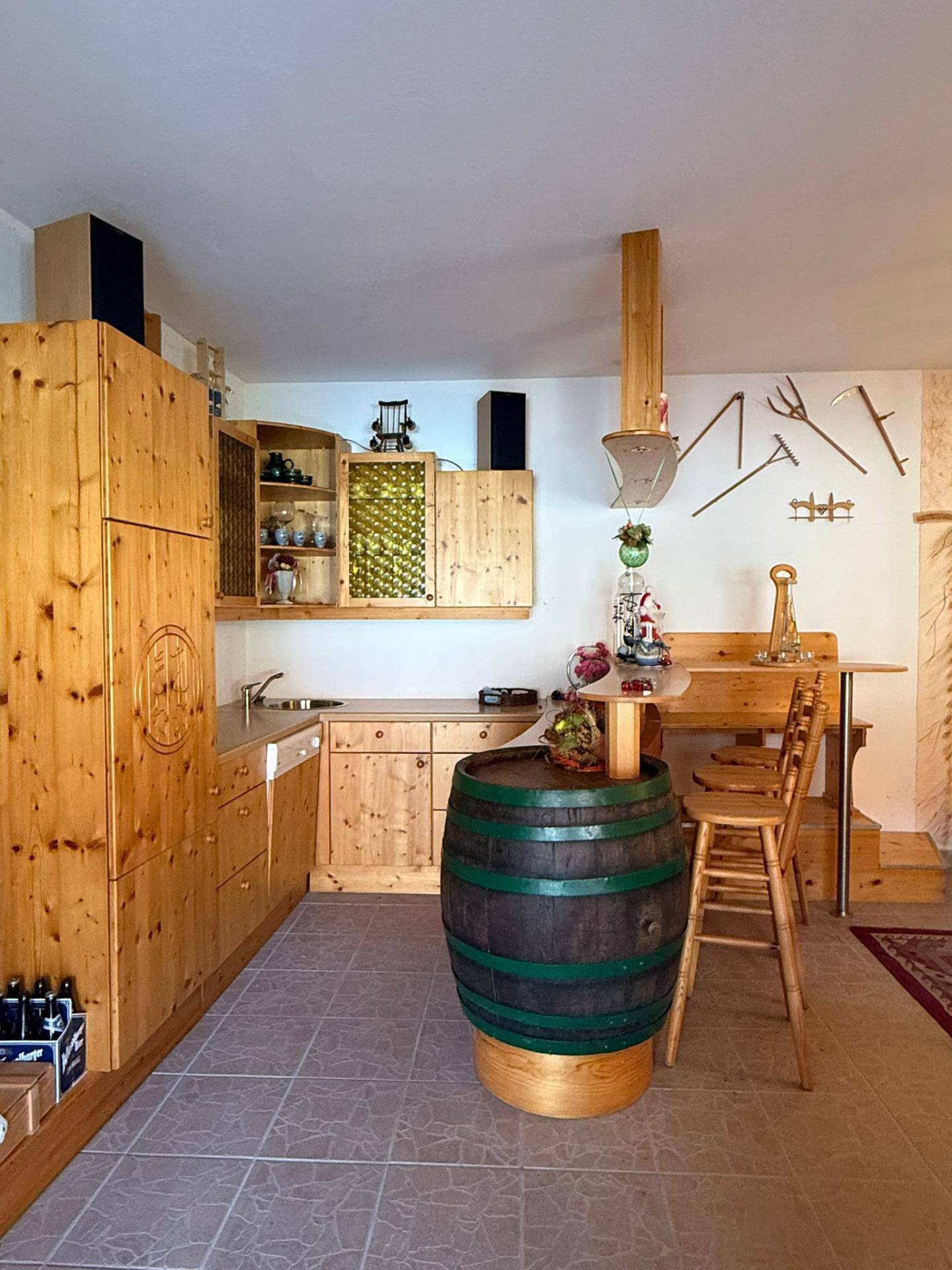 Rustikale Küche mit Holzmöbeln, Weinfass als Tisch und traditionellen Dekorationen.
