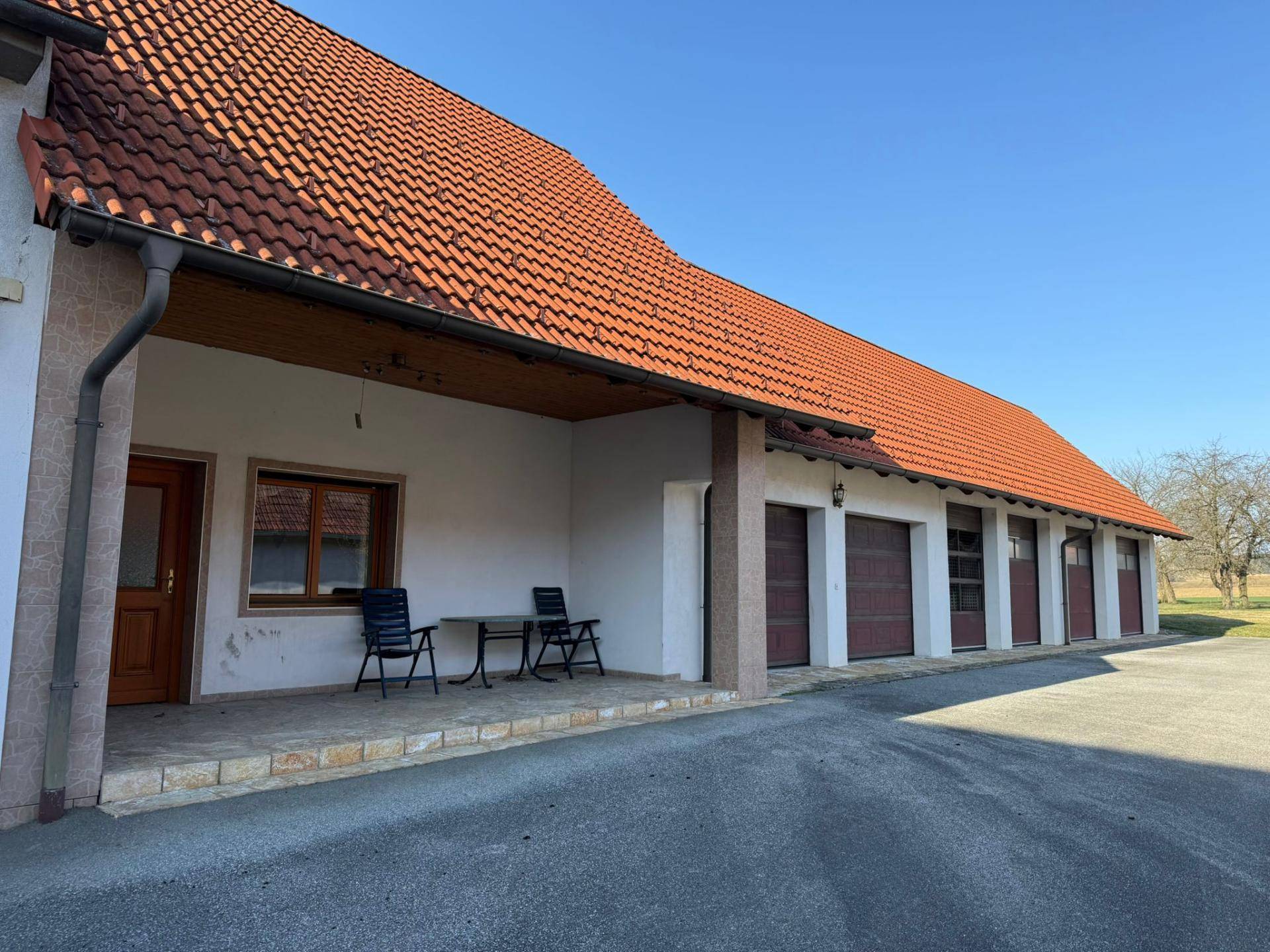Gebäude mit mehreren Garagen und überdachtem Sitzbereich im Freien.