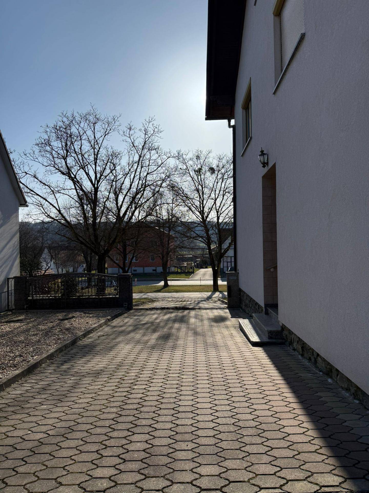Gepflasterte Auffahrt neben dem Haus mit Blick auf die ländliche Umgebung.