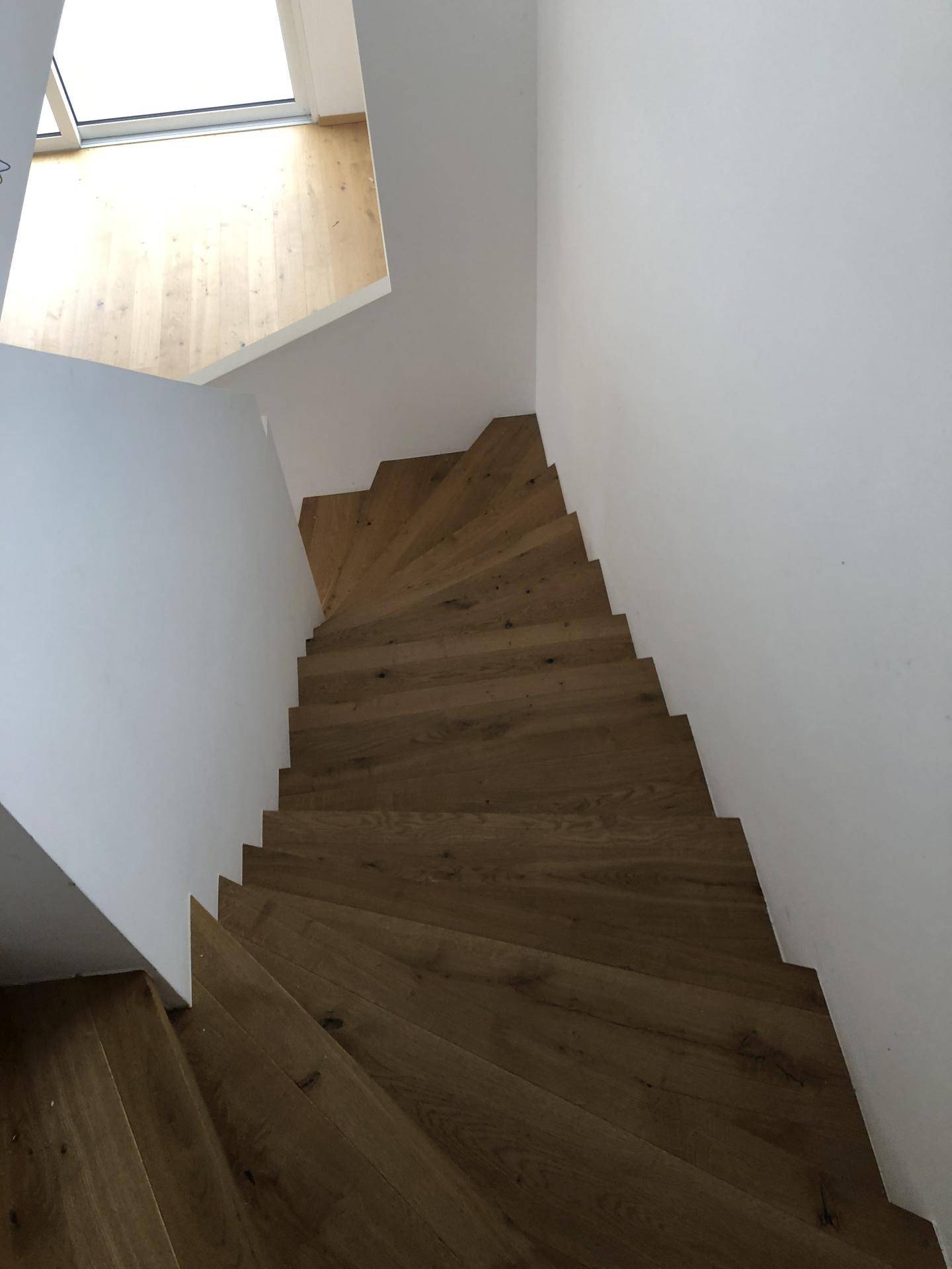 Moderne Holztreppe mit hellem Oberlicht, die die verschiedenen Etagen verbindet.