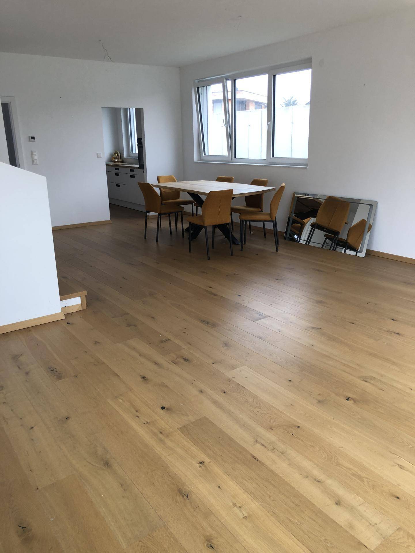 Heller Essbereich mit Holzboden, großem Esstisch und Verbindung zur Küche.