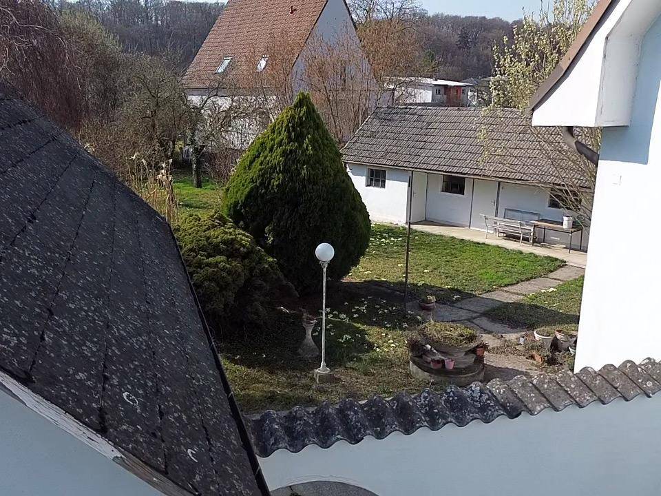 Blick von oben in den Garten mit gepflegter Rasenfläche und einem kleinen Nebengebäude.