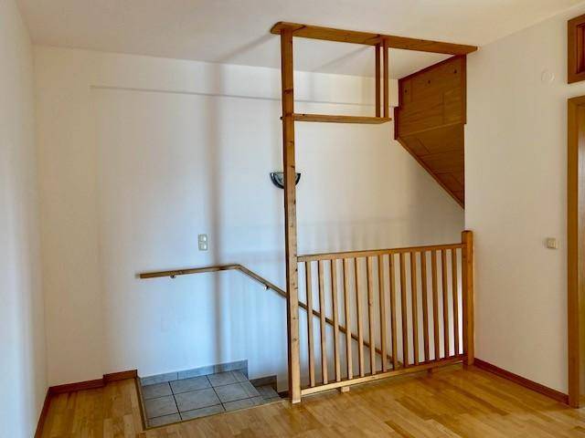 Treppenhaus mit Holzgeländer und Parkettboden, führt zu den oberen Etagen des Hauses, hell und offen.