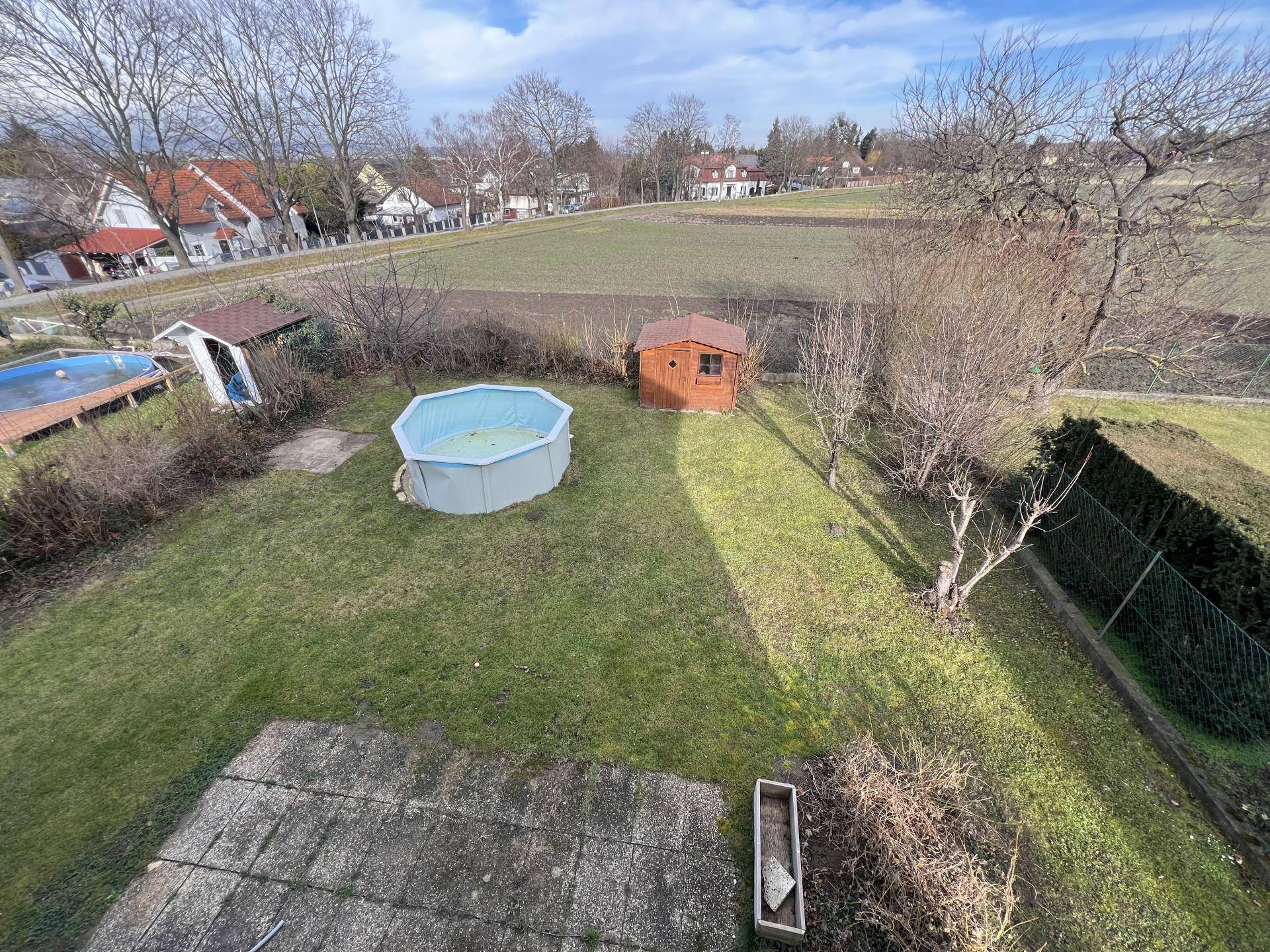 Gartenbereich von oben mit Rasen, Aufstellpool und Gartenhaus, umgeben von Natur.