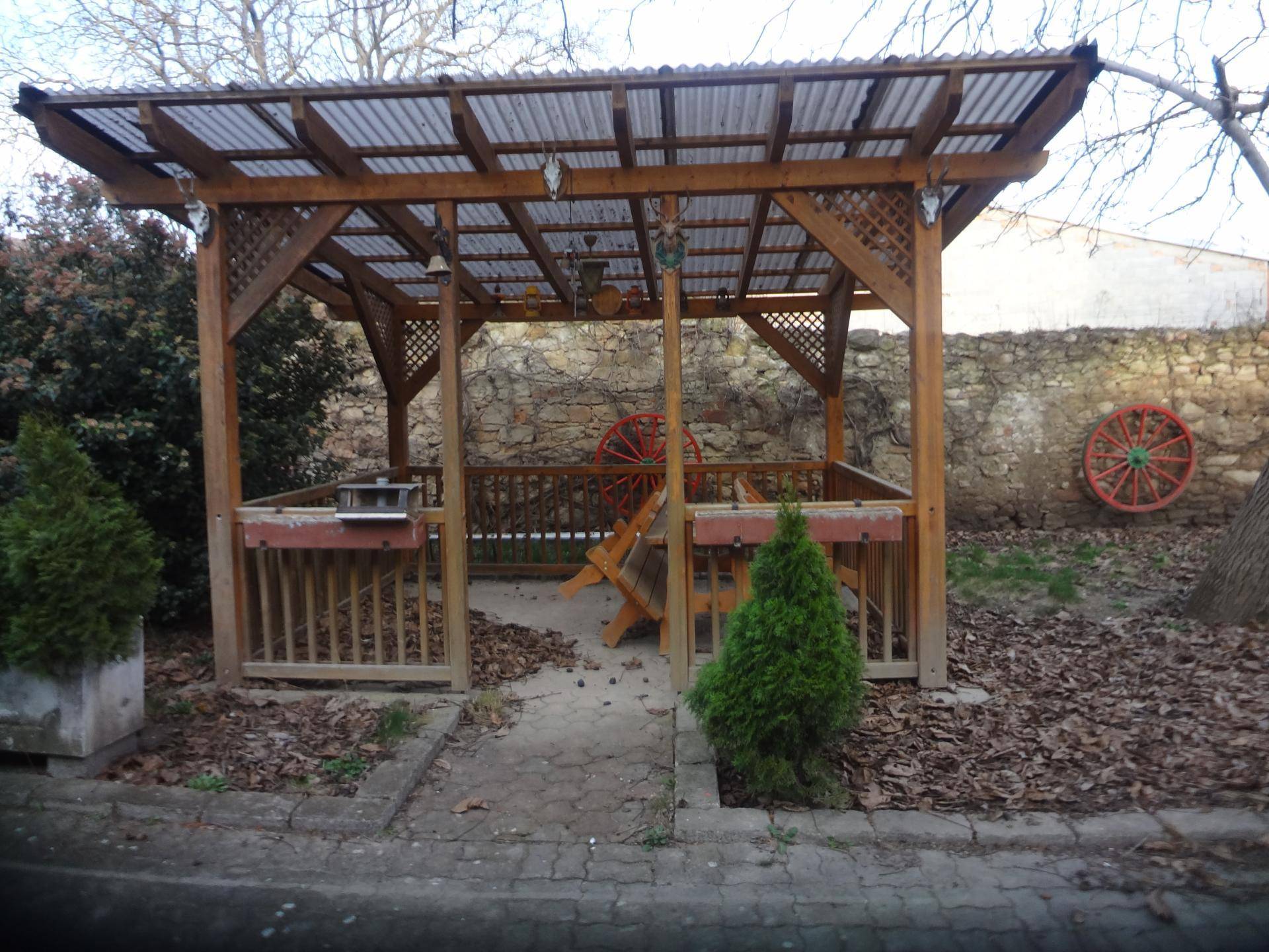 Hölzerner Pavillon im Garten mit Wellblechdach und rustikaler Dekoration.