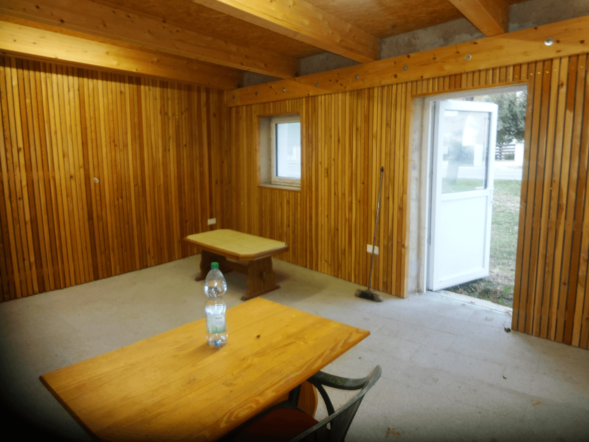 Renovierter Raum mit Holzvertäfelung, Holzbalken und einfacher Einrichtung.
