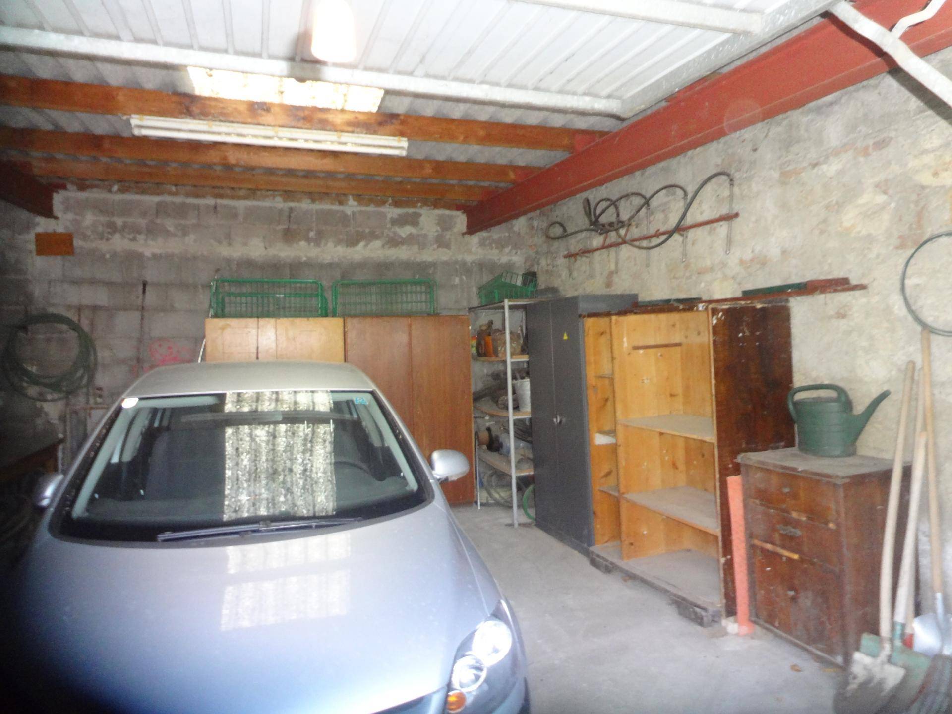 Geräumige Garage mit Betonboden, Lagerregalen und einem geparkten Auto.