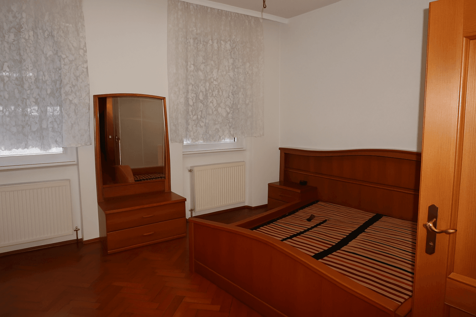 Schlafzimmer mit Holzparkett, Doppelbett und passendem Schminktisch.
