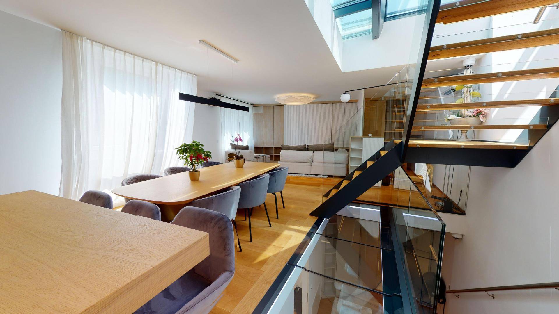 Heller Wohn- und Essbereich mit modernem Esstisch, Holzparkett und eleganter Glastreppe.