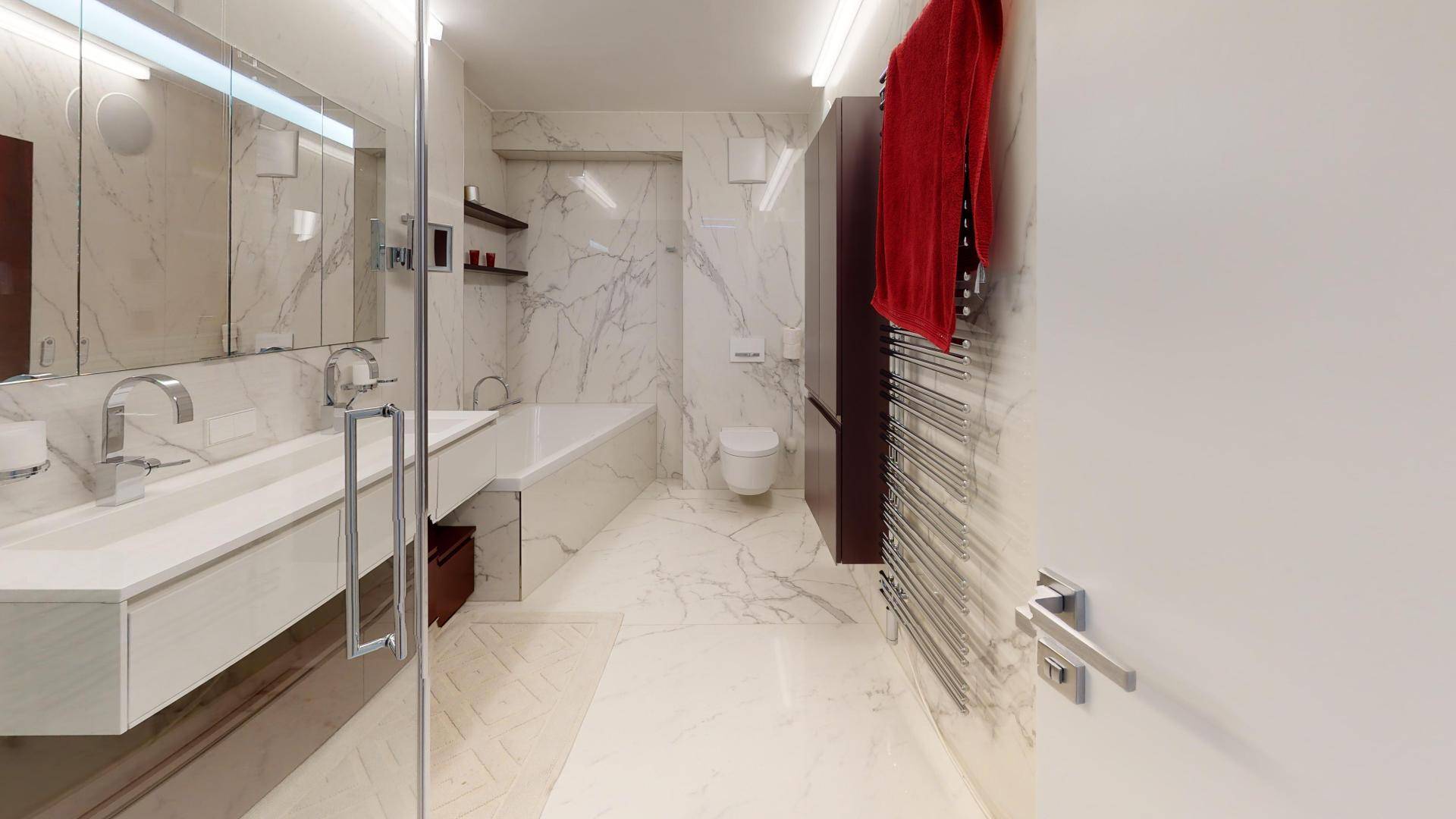 Elegantes Badezimmer mit Marmorfliesen, Doppelwaschbecken, Badewanne und beheiztem Handtuchhalter.