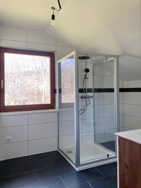 Helles Badezimmer mit Duschkabine, Fenster und modernen Fliesen in Weiß und Anthrazit.