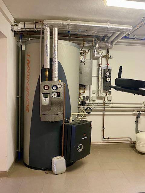 Technikraum mit großem Warmwasserspeicher und komplexer Rohrleitungsinstallation.