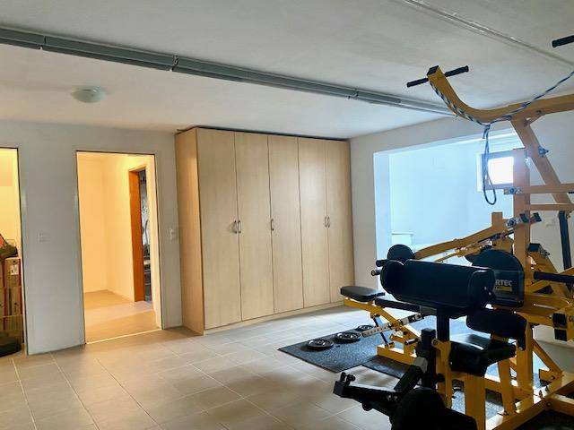 Fitnessraum im Untergeschoss mit Sportgeräten und integrierten Schränken.