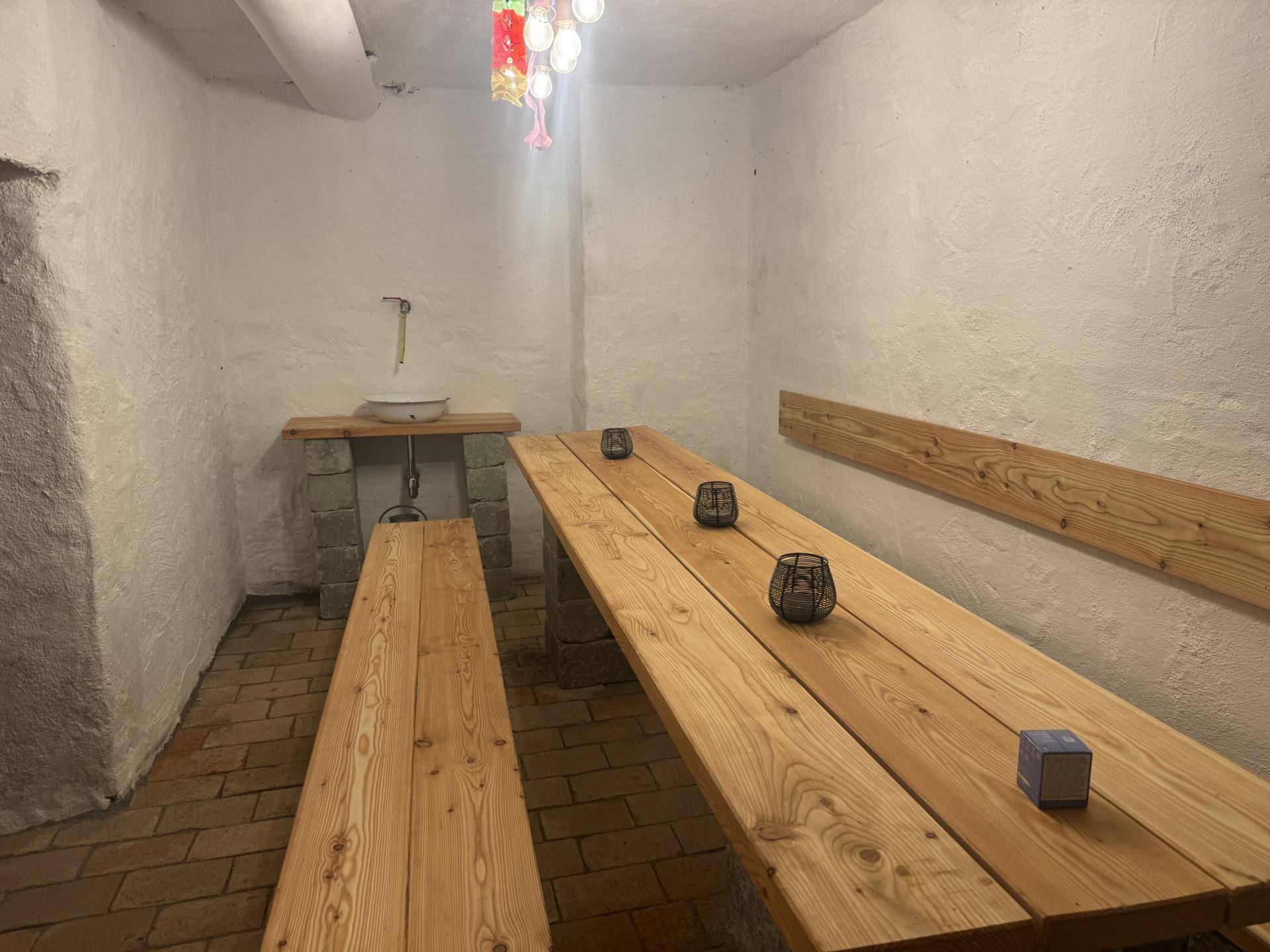 Rustikaler Raum im Untergeschoss mit Holztischen und Bänken, ideal für gesellige Runden.