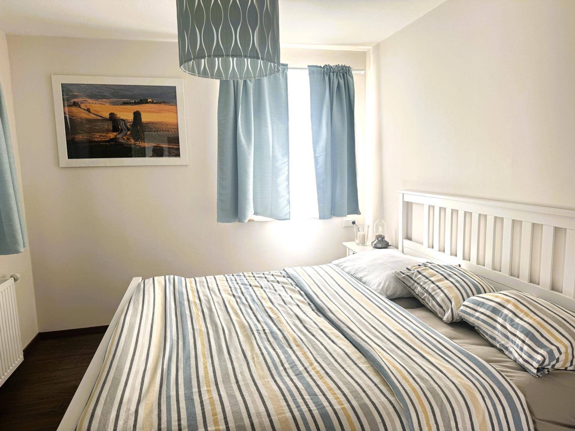 Gemütliches Schlafzimmer mit Doppelbett, hellen Wänden und einem Fenster für natürliches Licht.
