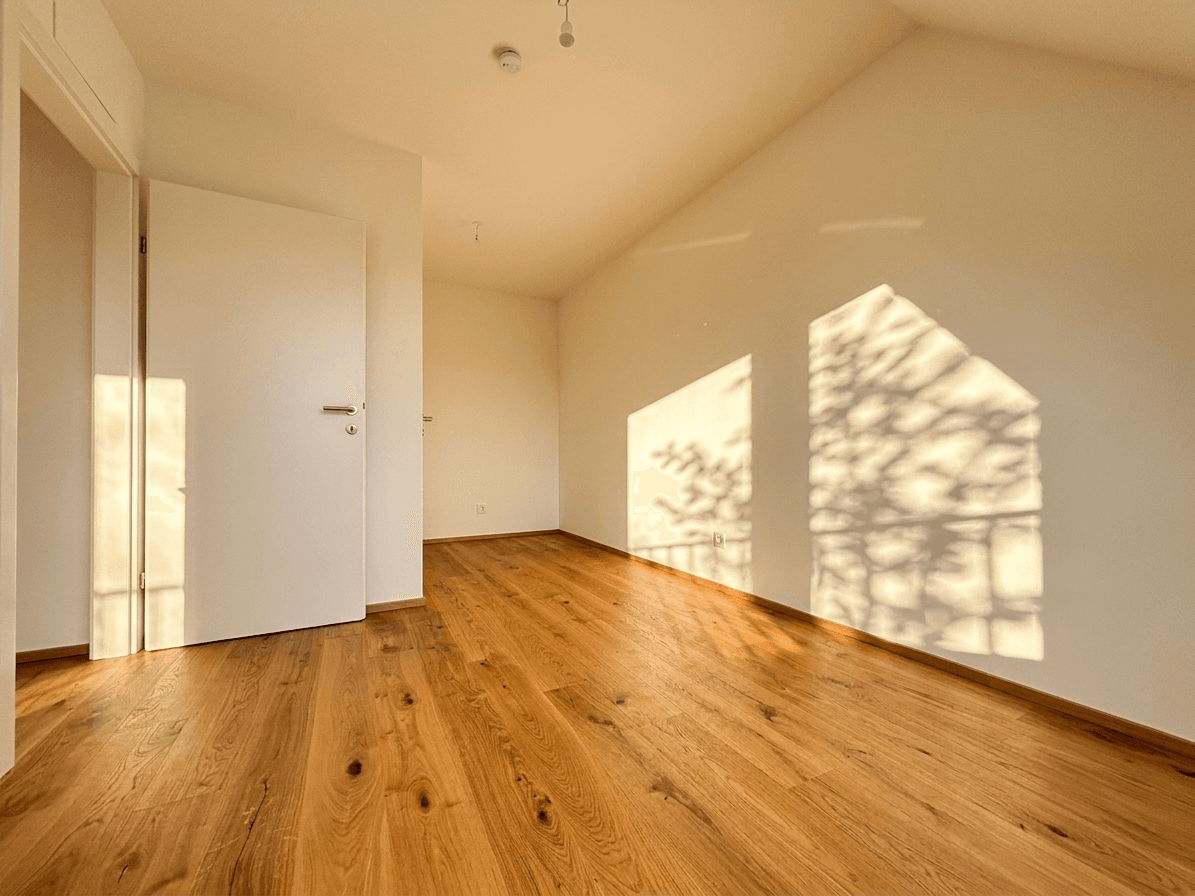 Geräumiges Zimmer mit Holzboden und viel natürlichem Licht, geeignet als Schlaf- oder Kinderzimmer.