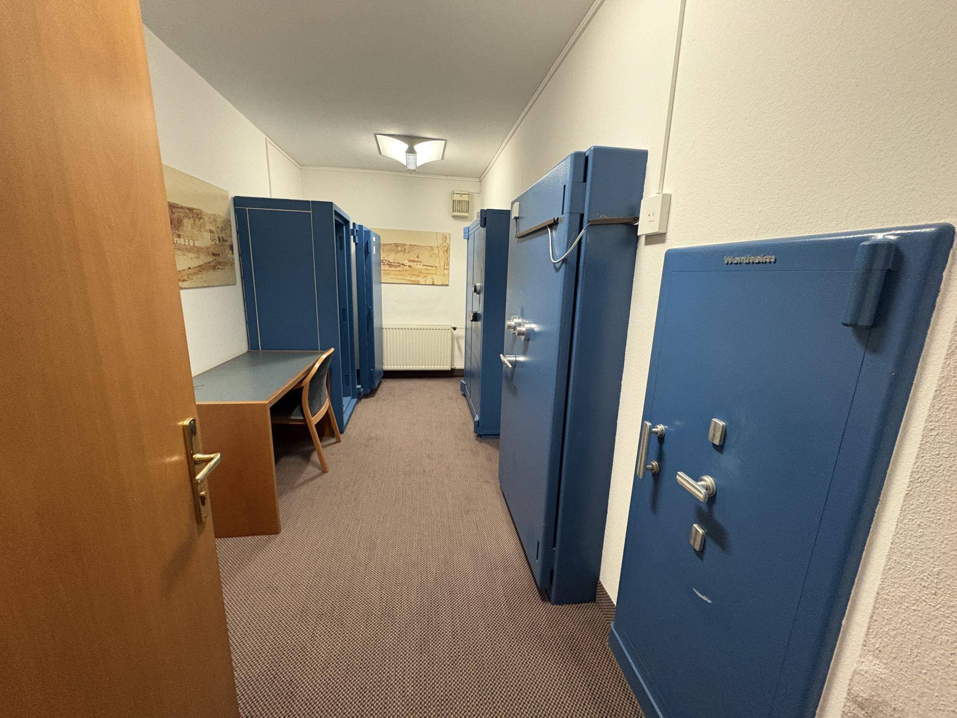 Sicherer Kellerraum mit mehreren großen blauen Tresoren und einem Schreibtisch.