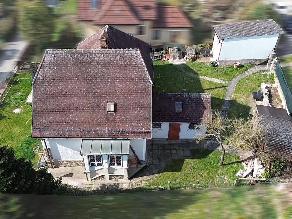 Luftaufnahme des Hauses von hinten mit Garten, Terrasse und Nebengebäuden.